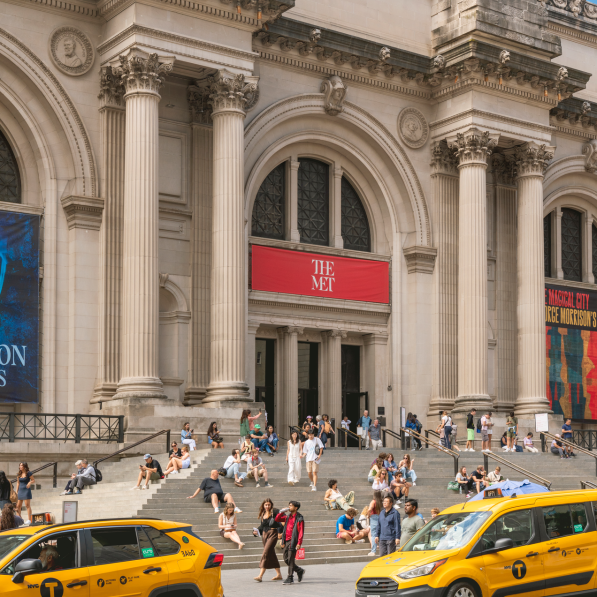The Metropolitan Museum of Art in NYC with cars parked in front of the stairs leading to the entrance