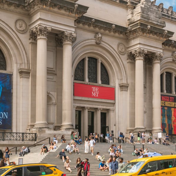 The Metropolitan Museum of Art in NYC with cars parked in front of the stairs leading to the entrance
