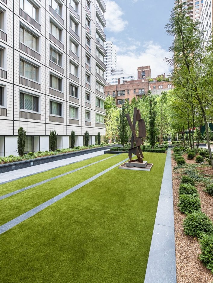 A vibrant, landscaped green space behind an apartment building in NYC