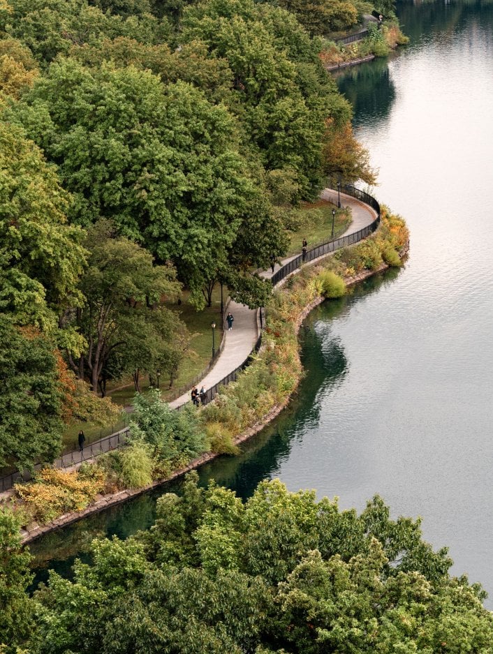 An aerial view of a path in Central Park beside calm water